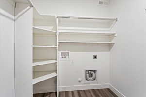 Laundry area with hookup for an electric dryer, hookup for a gas dryer, hardwood / wood-style flooring, and hookup for a washing machine