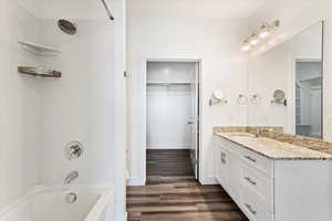 Bathroom with vanity, hardwood / wood-style flooring, and bathtub / shower combination