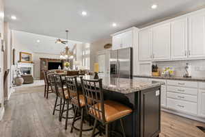 Kitchen with a kitchen bar, stainless steel fridge, a fireplace, light hardwood / wood-style floors, and a center island