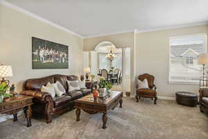 Living room with decorative columns, carpet, a chandelier, and ornamental molding