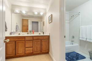 Bathroom with shower / washtub combination, tile patterned flooring, and dual bowl vanity