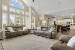 Living room featuring an inviting chandelier, carpet flooring, and high vaulted ceiling