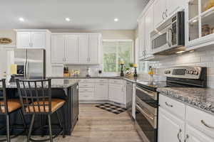 Kitchen featuring white cabinetry, stainless steel appliances, and backsplash