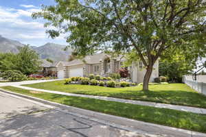 View of front of house with a mountain view, a garage, and a front lawn