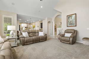 Living room featuring ornate columns, carpet flooring, and vaulted ceiling