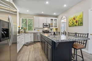 Kitchen featuring white cabinetry, a center island, backsplash, light hardwood / wood-style floors, and appliances with stainless steel finishes