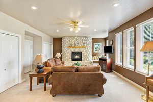 Living room featuring light carpet, a fireplace, and plenty of natural light