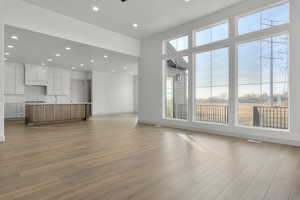 Unfurnished living room featuring light hardwood / wood-style flooring, a high ceiling, and sink