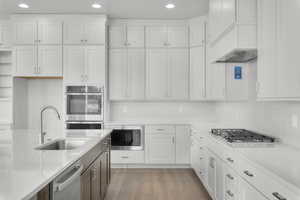 Kitchen featuring sink, stainless steel appliances, light stone counters, decorative backsplash, and white cabinets