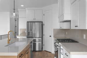 Kitchen with white cabinetry, sink, pendant lighting, and appliances with stainless steel finishes