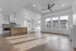 Kitchen with a large island, stainless steel microwave, decorative light fixtures, a tray ceiling, and white cabinets