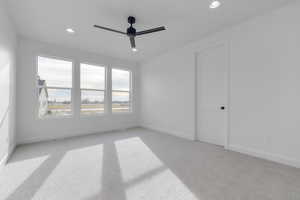 Unfurnished room featuring ceiling fan and light carpet