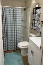 Bathroom featuring hardwood / wood-style flooring, toilet, and a shower with curtain