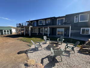 Rear view of property featuring a patio area, an outdoor fire pit, a storage unit, and a balcony