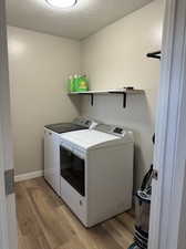 Washroom with a textured ceiling, hardwood / wood-style flooring, and washer and clothes dryer