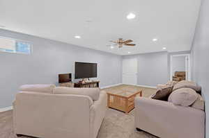 Carpeted living room featuring ceiling fan