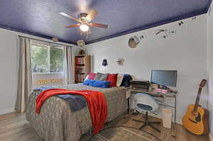 Bedroom featuring ceiling fan, hardwood / wood-style floors, and a textured ceiling