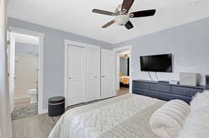 Bedroom featuring light wood-type flooring, ceiling fan, connected bathroom, and a closet