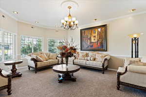 Living room with crown molding, carpet, and a chandelier