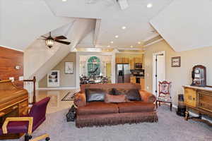 Carpeted living room with ceiling fan and crown molding