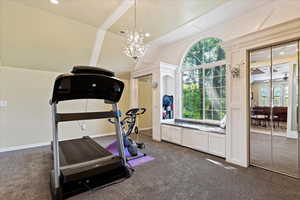 Bedroom with a notable chandelier, dark colored carpet, plenty of natural light, and vaulted ceiling