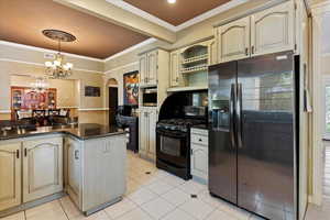 Kitchen with light tile patterned flooring, an inviting chandelier, black appliances, hanging light fixtures, and ornamental molding