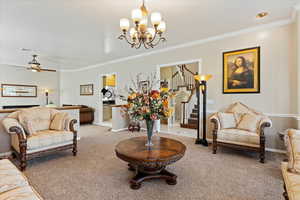 Carpeted living room featuring crown molding and a chandelier