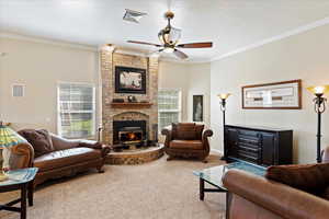 Living room with carpet floors, a fireplace, brick wall, ceiling fan, and ornamental molding