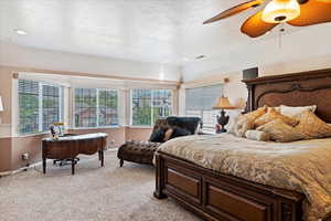 Bedroom with light carpet, a textured ceiling, and ceiling fan