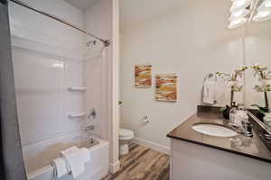 Full bathroom with shower / tub combo with curtain, vanity, wood-type flooring, and toilet