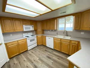 Kitchen with sink, light wood-type flooring, and white appliances