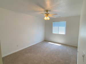 Carpeted bedroom featuring a textured ceiling and ceiling fan