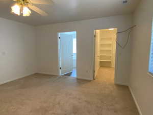 Bedroom a spacious closet, carpet flooring, and ceiling fan