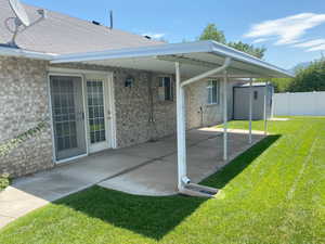 Back of house featuring a patio, a lawn, and a storage shed