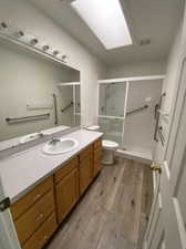 Bathroom featuring vanity, an enclosed shower, toilet, and hardwood / wood-style floors