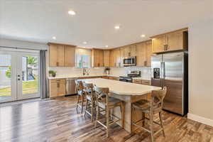 Kitchen with a kitchen breakfast bar, a kitchen island, dark hardwood / wood-style floors, and stainless steel appliances