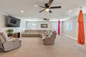 Carpeted living room featuring a textured ceiling and ceiling fan