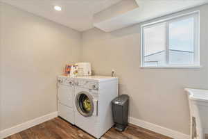 Clothes washing area with washer and clothes dryer and dark hardwood / wood-style floors