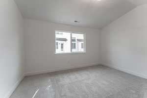 Carpeted spare room with lofted ceiling