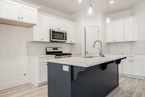 Kitchen featuring white cabinets, appliances with stainless steel finishes, and hanging light fixtures