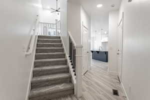 Stairs with hardwood / wood-style flooring, ceiling fan, and sink