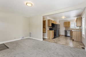 Kitchen featuring light brown cabinetry, sink, black appliances, and light colored carpet