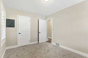 Unfurnished bedroom featuring carpet floors, a closet, and electric panel