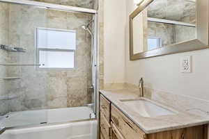 Bathroom with bath / shower combo with glass door and vanity