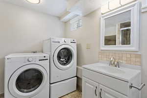 Washroom featuring light tile patterned floors, washing machine and clothes dryer, and sink