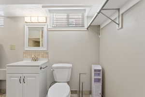 Bathroom featuring a healthy amount of sunlight, vanity, backsplash, and toilet