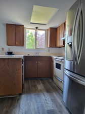 Kitchen with dark hardwood / wood-style floors, electric range, stainless steel fridge, and sink