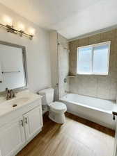 Full bathroom with vanity, wood-type flooring, tiled shower / bath, and toilet