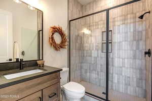 Bathroom with a shower with shower door, vanity, and toilet