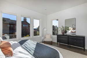 Bedroom with dark hardwood / wood-style flooring and multiple windows